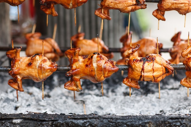 Photo rôti de poulet entier sur un poêle à charbon tournant