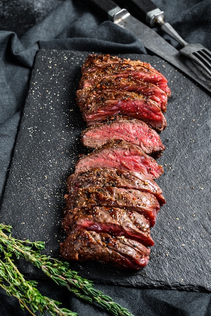 Photo rôti de steak de vegas en tranches rôti grillé. boeuf à la viande de marbre. fond noir. vue de dessus