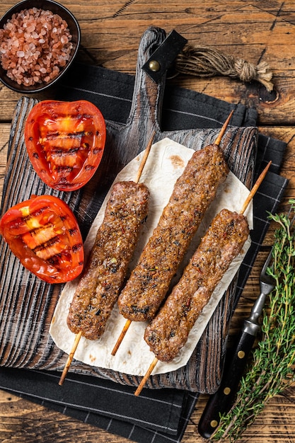 Rôti turc Adana shish kebab sur une planche avec tomate grillée vue de dessus de fond en bois