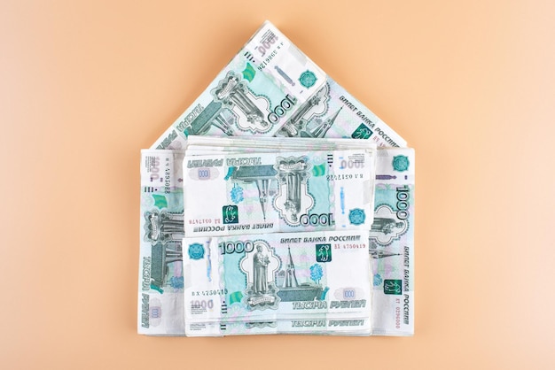 Roubles. Argent russe en forme de maison sur fond beige. Notion de prêt immobilier