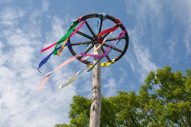 Roue en bois avec des rubans colorés sur fond de ciel bleu. Célébration slave.