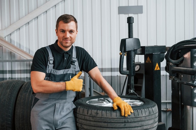 Roue cassée Un homme en uniforme travaille dans le service automobile