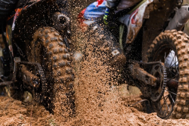 La roue d'une moto de motocross de course roule le long de la piste de course à grande vitesse et des éclaboussures s'envolent sous la roue