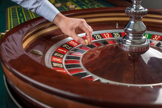 Roue de roulette et main de croupier avec boule blanche au casino