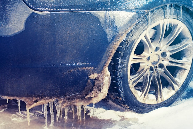 Roue de voiture gros plan dans les glaçons et la pluie verglaçante. Glace sévère.