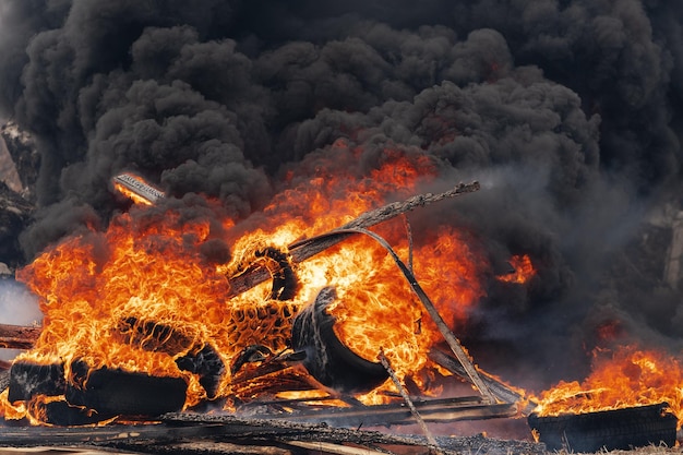 Roues d'automobile brûlantes flamme de feu rouge et nuages de fumée noire dans le ciel