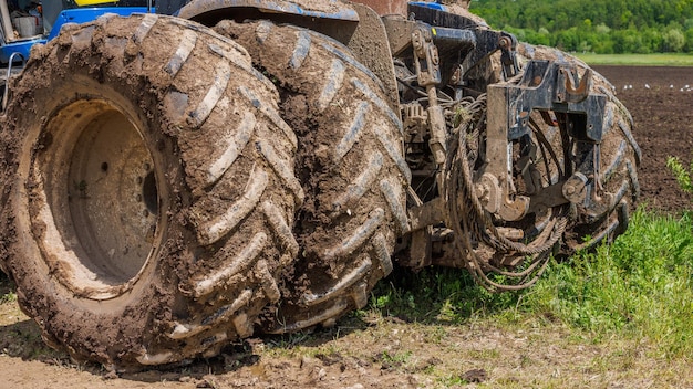 Roues doubles sales du tracteur agricole sur un chemin de terre à la journée d'été ensoleillée