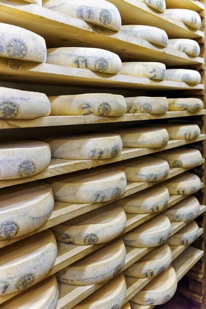 Roues de vieillissement du fromage sur des étagères en bois dans la cave d'affinage de la crémerie de Franche Comté en France