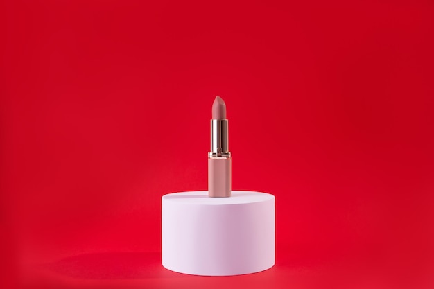 Rouge à lèvres beige nude sur podium blanc sur fond rouge Modèle de conception de produit cosmétique de mode