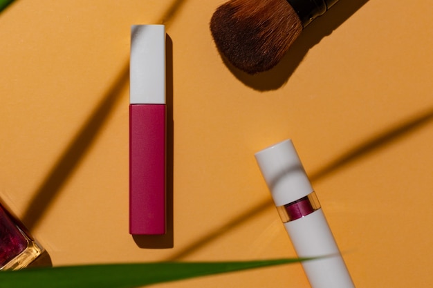 Rouge à lèvres sur fond orange avec feuillage édition estivale pour la publicité de produits cosmétiques