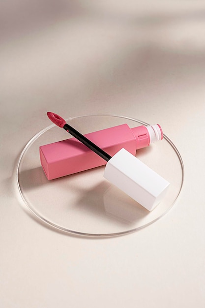 Rouge à lèvres liquide rose et pinceau applicateur avec tube ouvert Produit cosmétique de maquillage Fond chaud neutre