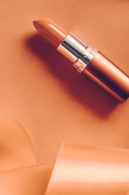 Rouge à lèvres de luxe et ruban de soie sur fond de vacances orange maquillage et cosmétiques flatlay pour la conception de produits de marque de beauté