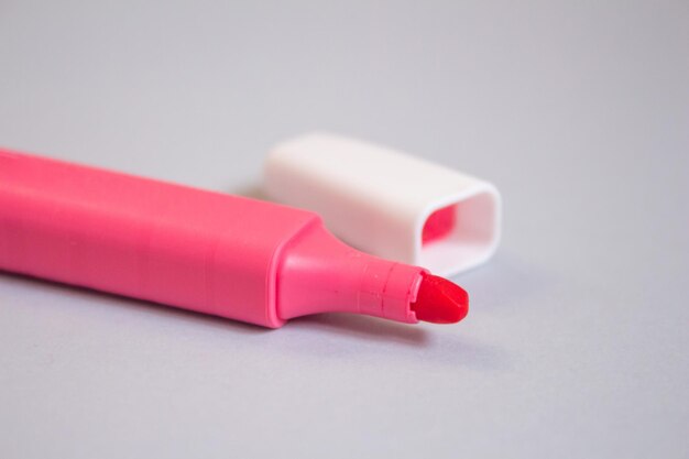 Un rouge à lèvres rose est posé sur une table à côté d'un tube de rouge à lèvres blanc.