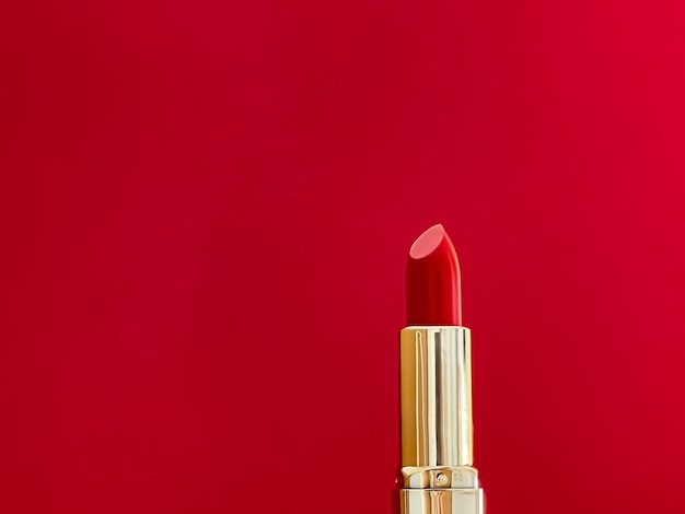 Rouge à lèvres rouge en tube doré sur fond de couleur maquillage de luxe et cosmétiques pour la conception de produits de marque de beauté