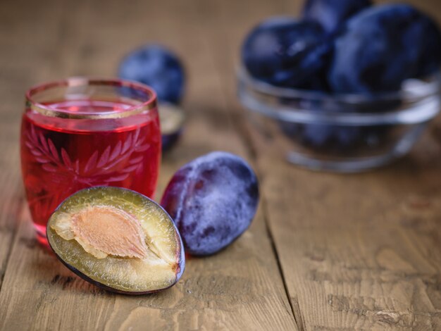 Rouge vif l'apéritif de prune sur une table en bois.