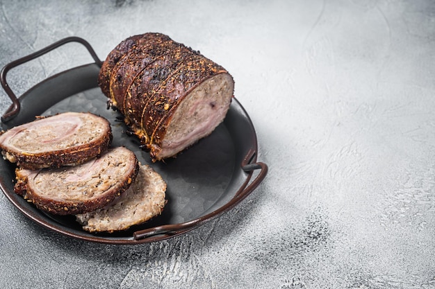 Roulade de viande de porc rôtie en tranches sur un plateau en acier Fond blanc Vue de dessus Espace de copie