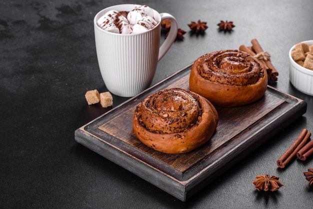 Rouleau de cannelle fraîchement cuit avec des épices et une garniture de cacao sur fond noir. Brioches au cannab. Petit déjeuner suédois.