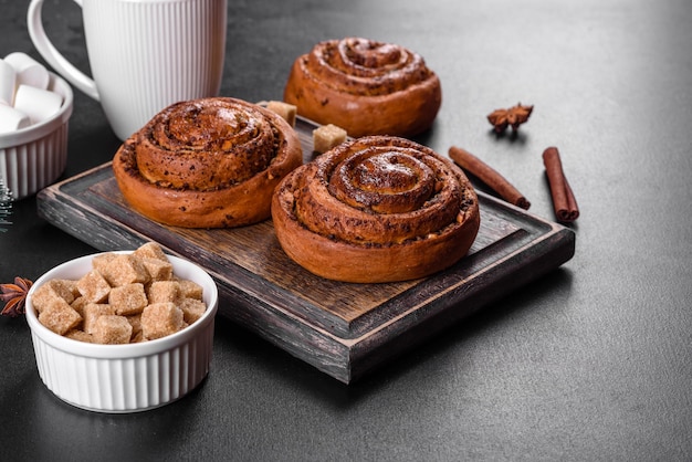 Rouleau de cannelle fraîchement cuit avec des épices et une garniture de cacao sur fond noir. Brioches au cannab. Petit déjeuner suédois.