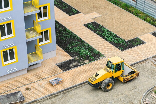 Un rouleau compresseur nivelle et compacte le sable avant que l'asphalte ne soit posé sur un chantier de construction