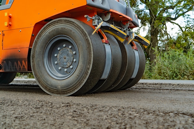 Photo rouleau compresseur orange pour asphalte à quatre roues se dresse sur la route au jour