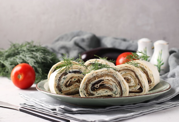 Rouleau de lavash aux aubergines, ail et fromage à la crème sur apéritif gris et festif.