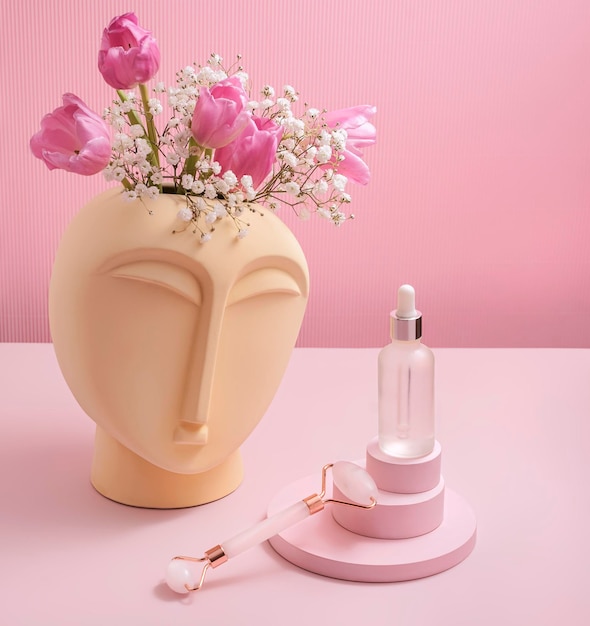 Rouleau de massage pour le visage en quartz rose avec des bouteilles d'huile cosmétique ou de sérum Le concept de soins de la peau à la maison