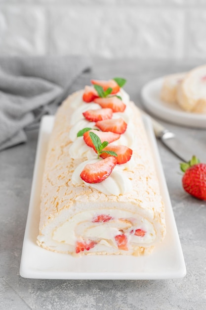 Rouleau de meringue Pavlova gâteau à la crème et fraises fraîches sur un fond gris Copier l'espace