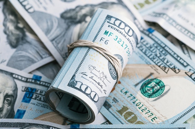Un rouleau de nos billets de cent dollars posés sur une pile d'argent des États-Unis d'Amérique