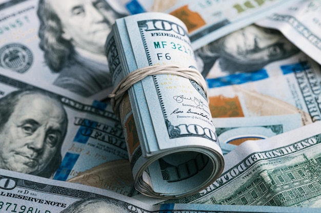 Un rouleau de nos billets de cent dollars posés sur une pile d'argent des États-Unis d'Amérique