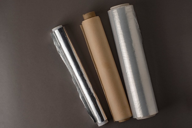Un rouleau de papier d'aluminium, un rouleau de film alimentaire et un rouleau de papier sulfurisé.