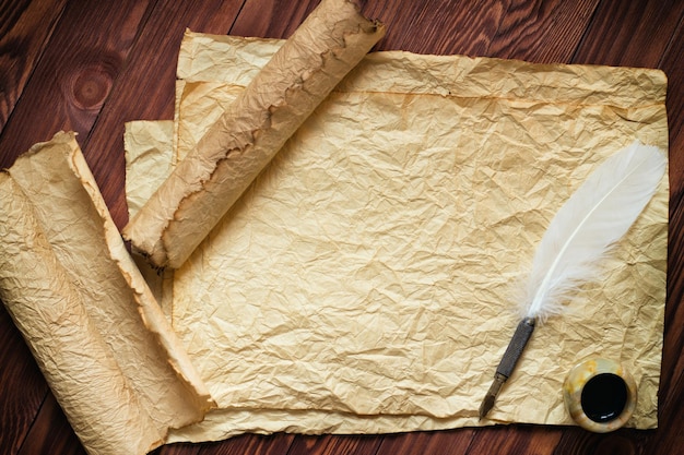 Rouleau de papier avec stylo plume et pot d'encre sur fond de bois