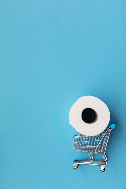 Rouleau de papier toilette blanc avec un caddie sur fond bleu