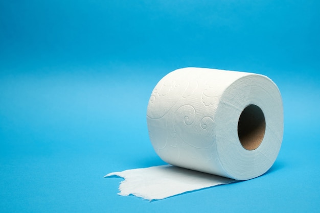 Rouleau de papier toilette blanc déchiré sur fond bleu minimaliste