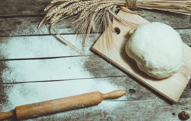 Photo rouleau à pâte et épis de blé sur le vieux fond en bois fariné