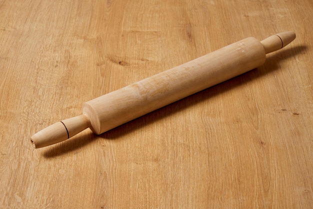 Un rouleau à pâtisserie en bois est posé sur une table avec le dessus.