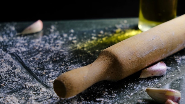 Rouleau à pâtisserie de cuisine avec de la farine sur fond sombre. nourriture noire