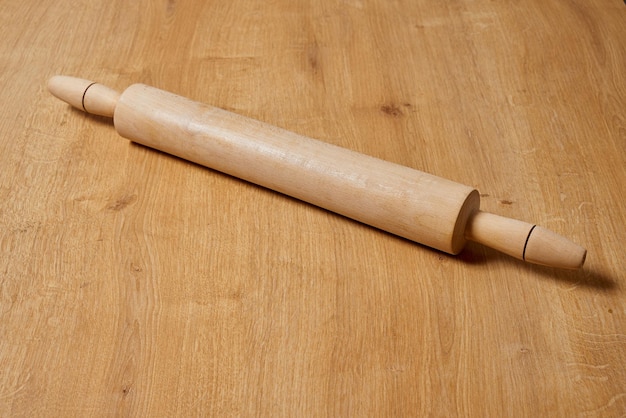 Un rouleau à pâtisserie est sur la table à côté d'une table en bois.