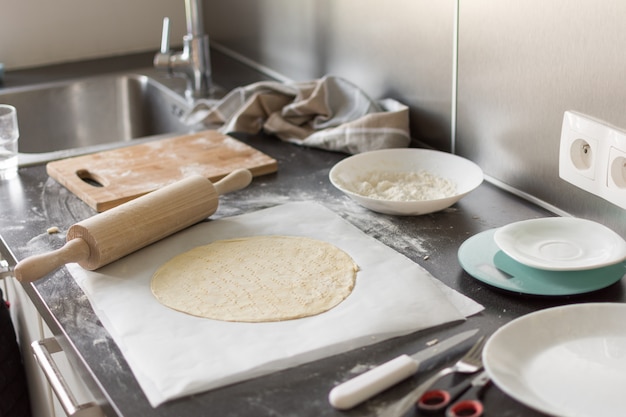 rouleau à pâtisserie avec de la farine sur la table de la cuisine avec des ingrédients.