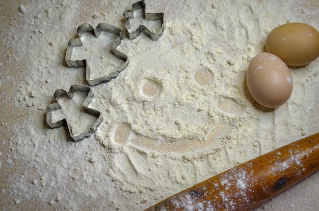 rouleau à pâtisserie sur la pâte et un sourire de farine