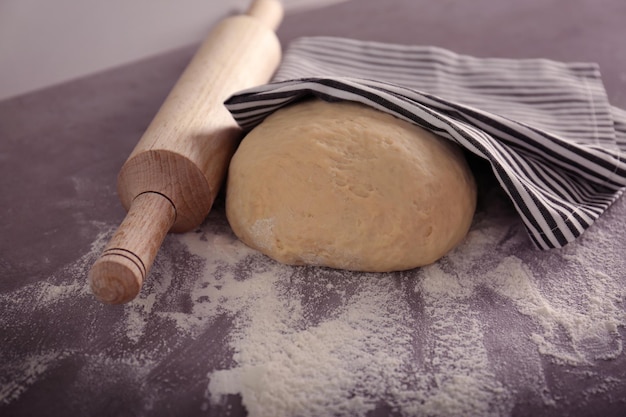 Rouleau à pâtisserie avec de la pâte sur la table de la cuisine