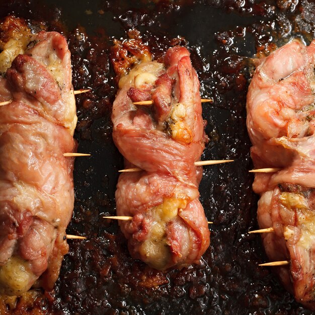 Rouleau de poulet frit avec du fromage et du bacon sur la plaque à pâtisserie du four.