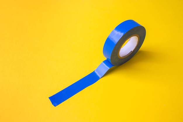 Rouleau de ruban adhésif en plastique bleu sur fond jaune. Fermer.