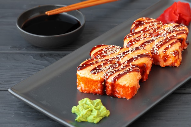 Rouleau de sushi cuit servi sur plaque noire sur table en bois