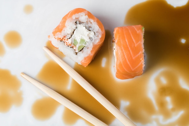 Rouleau de sushi dans des baguettes en gros plan de sauce soja