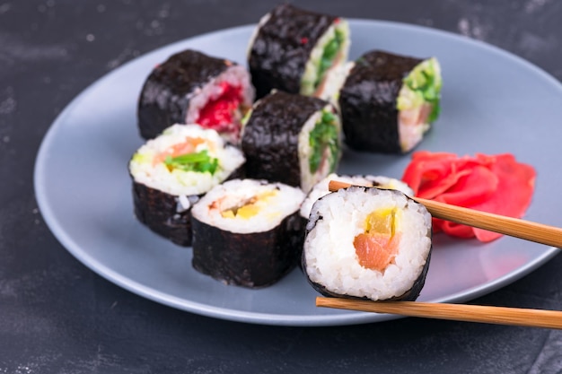 Rouleau de sushi avec de grandes baguettes sur un fond de plaque avec vue de dessus de rouleaux