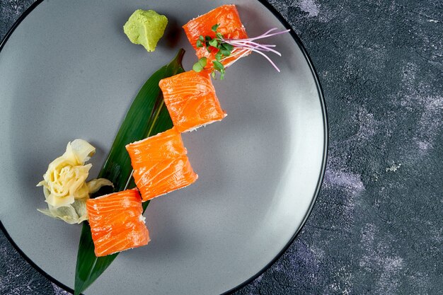 Rouleau De Sushi Japonais Au Saumon Et Fromage à La Crème. Rouler Philadelphie Dans Une Assiette Grise Sur Fond Noir. Vue De Dessus