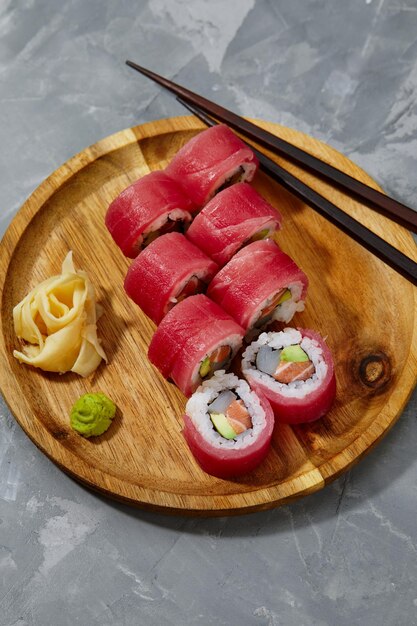 Rouleau de sushi Maguro au thon crevette saumon anguille fumée avocat fromage philadelphie sur fond noir menu sushi cuisine japonaise