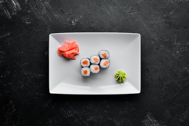 Photo rouleau de sushi maki au saumon cuisine japonaise vue de dessus sur un fond de pierre noire