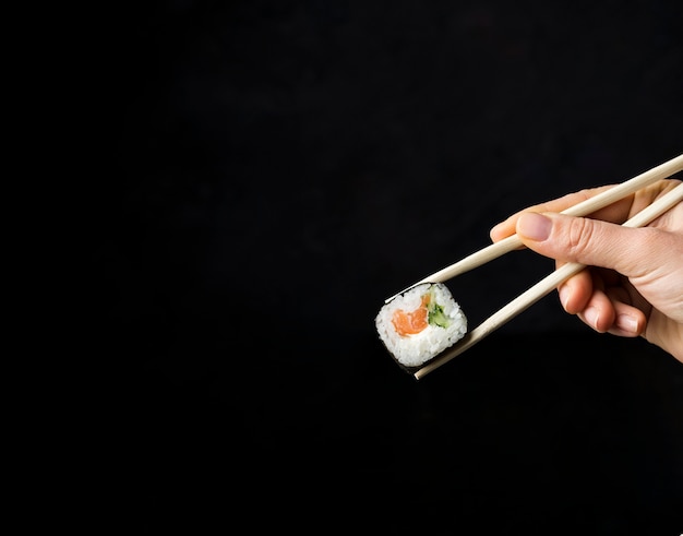 Rouleau de sushi minimaliste avec des légumes et du riz sur fond noir