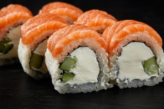 Rouleau de sushi de Philadelphie avec concombre de thon et fromage à la crème sur fond noir pour le menu Cuisine japonaise